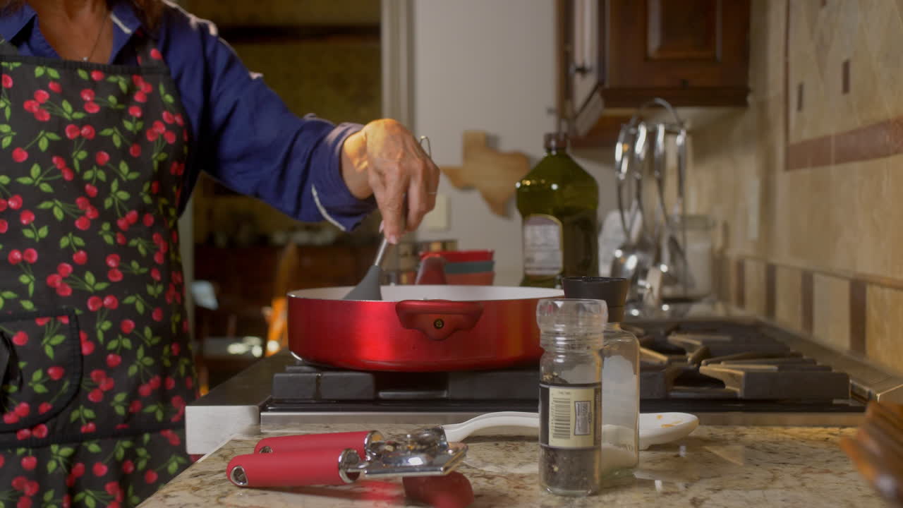 mujer agitando comida de cocina en una sartén roja dolly fuera