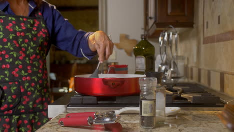 mujer agitando comida de cocina en una sartén roja dolly fuera