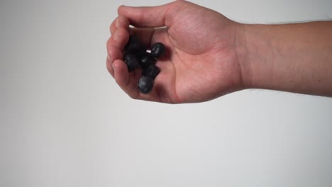 Single-hand-dropping-blueberries-in-slow-motion