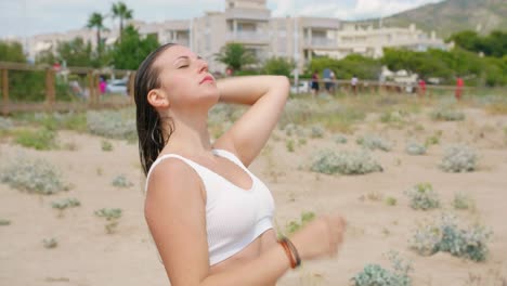 joven mujer rubia alisando su cabello mojado después de darse un chapuzón en el cálido mar mediterráneo