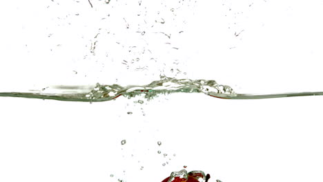 red apple plunging into water on white background
