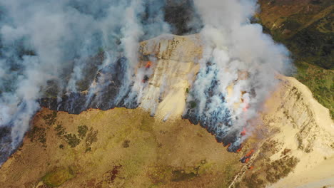 Aerial-drone-view-of-smoke-rising-from-a-wildfire-on-a-hillside