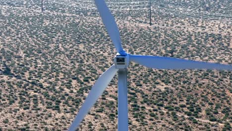 Rear-view-of-rotating-wind-turbine-generating-power-against-hot-arid-desert-landscape