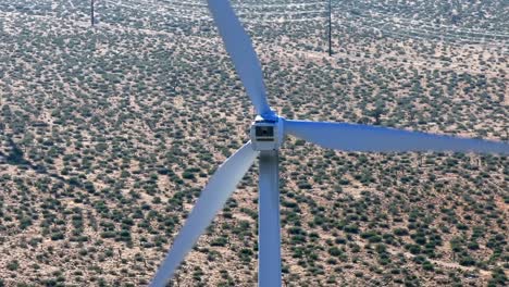 vista trasera de la turbina eólica giratoria que genera energía contra el paisaje desértico árido y caliente