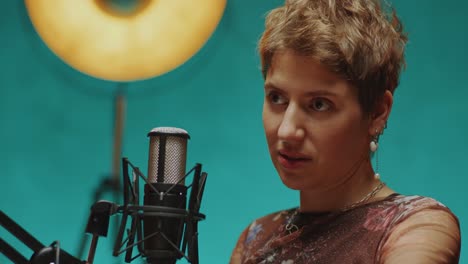 young woman giving podcast interview in modern recording studio