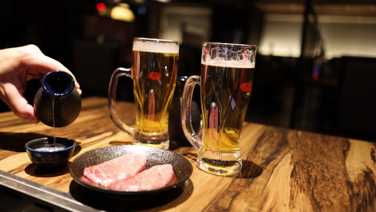 사람이 스테이크를 계절하고 그 위에 어두운 소스를 부어