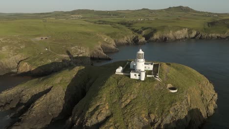 An-aerial-view-of-the-of-Strumble-Head-lighthouse-in-Pembrokeshire,-South-Wales,-on-a-sunny-summer-evening