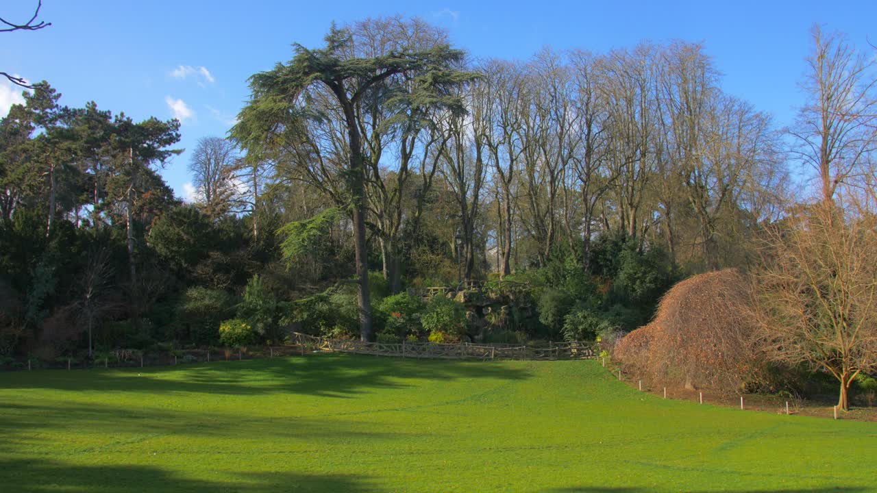 hermoso césped verde rodeado de árboles en el parque montsouris en parís francia - toma panorámica panorámica