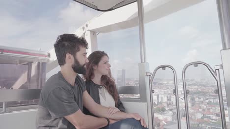 una pareja joven y romántica viajando sentada juntos en la rueda de ferris, tomando selfies y fotos del horizonte de bruselas, viajando hacia su destino.