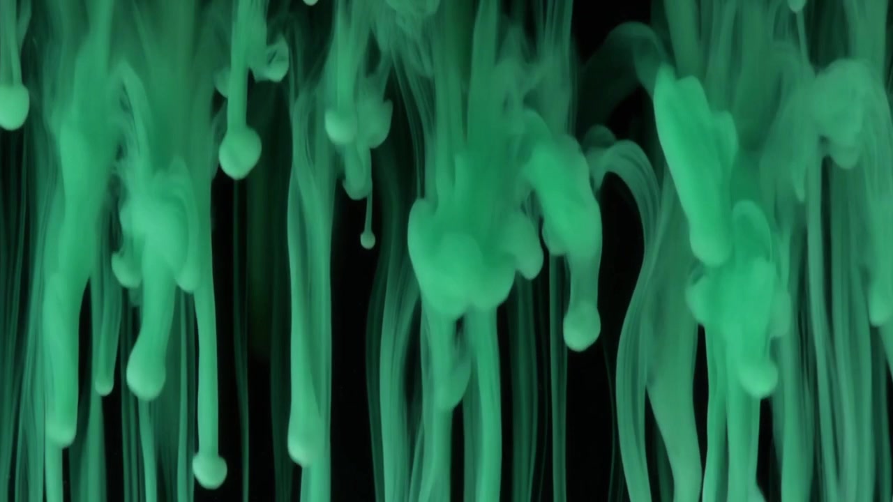 Gouttelettes d'encre verte se dissolvant dans l'eau sur fond noir