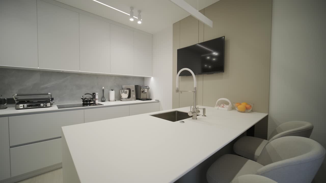 una lujosa cocina con una gran isla, un grifo de oro y una lámpara sputnik, electrodomésticos de acero inoxidable y encimeras de mármol blanco.