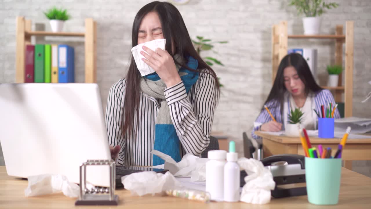Sick young asian office worker sneezes and coughs in the workplace in the office