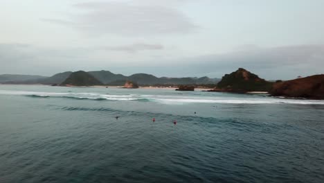 AERIAL-4K-Panning-Shot-of-Surfers-Floating-in-Waters-of-Lombok-Indonesia-at-Sunset