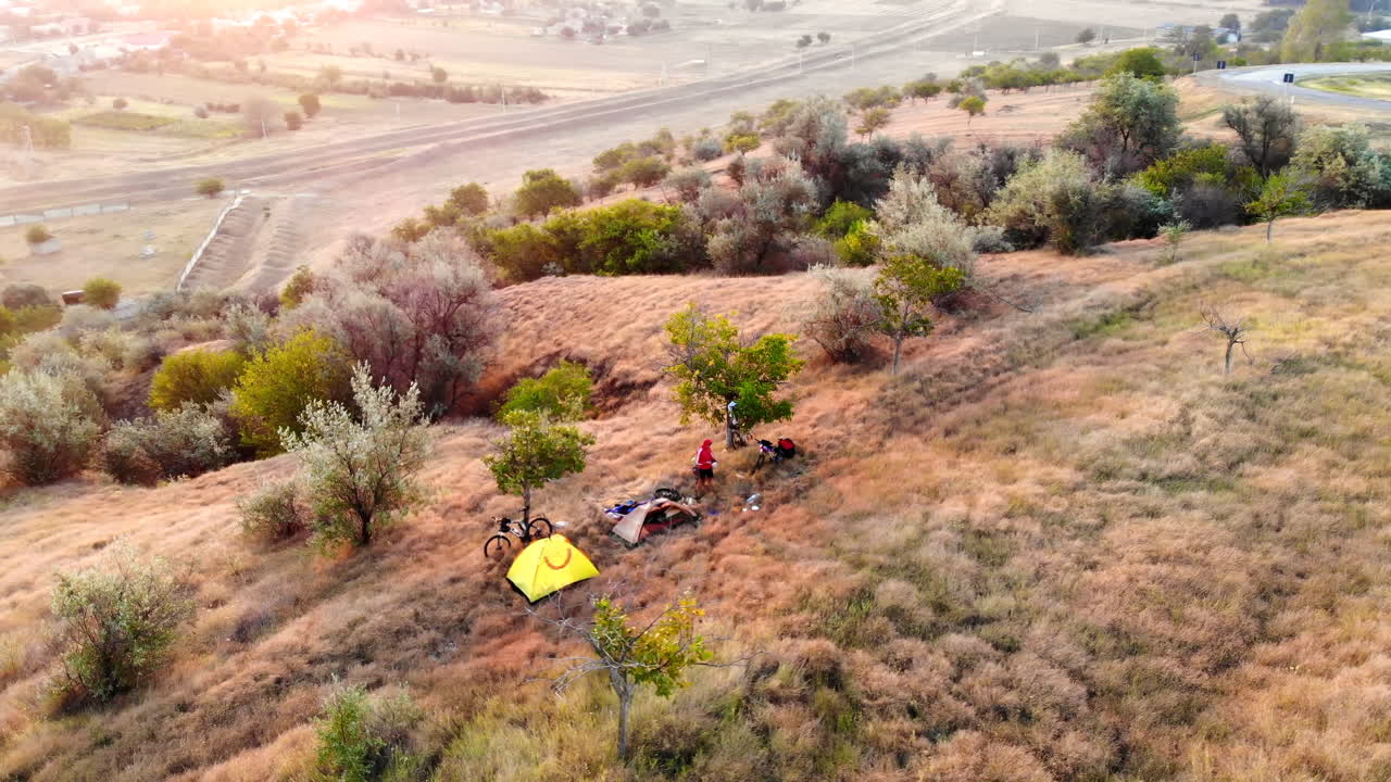 Aerial drone view of camping tents with people in the meadow. Beautiful sunset in Moldova. Greenery and village on background. Travel time idea