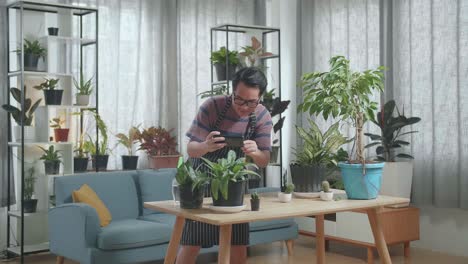 asian man holding smartphone and taking photos of plants at home