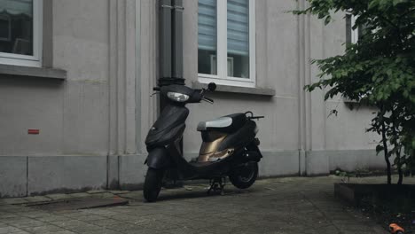 slow motion push-out shot of a black and gold scooter parked by a textured residential wall