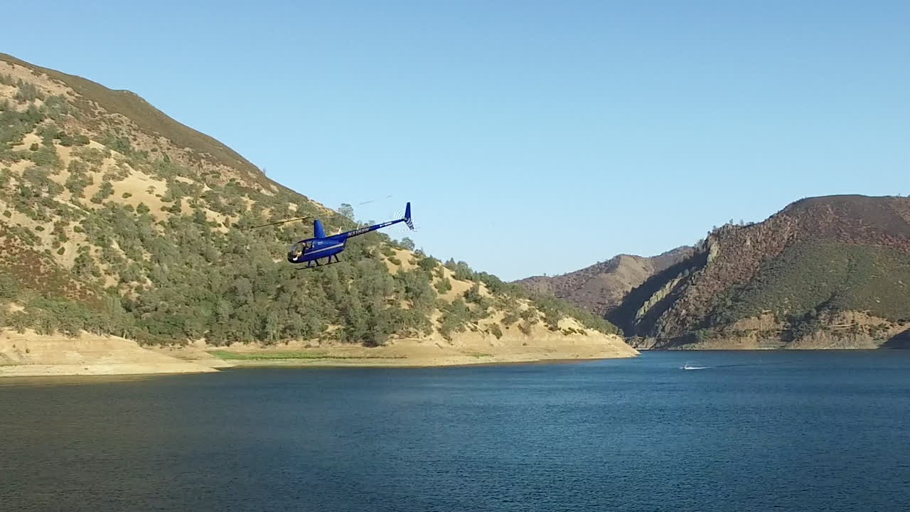 Helikopter berputar-putar di atas danau pegunungan yang jernih.