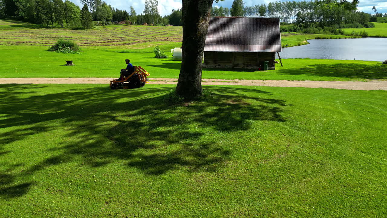 Man Mowing Lawn on a Sunny Summer Day in the Countryside