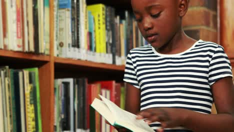 little girl reading book in library