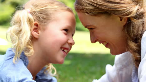 madre feliz acostada en la hierba con su niña en el parque