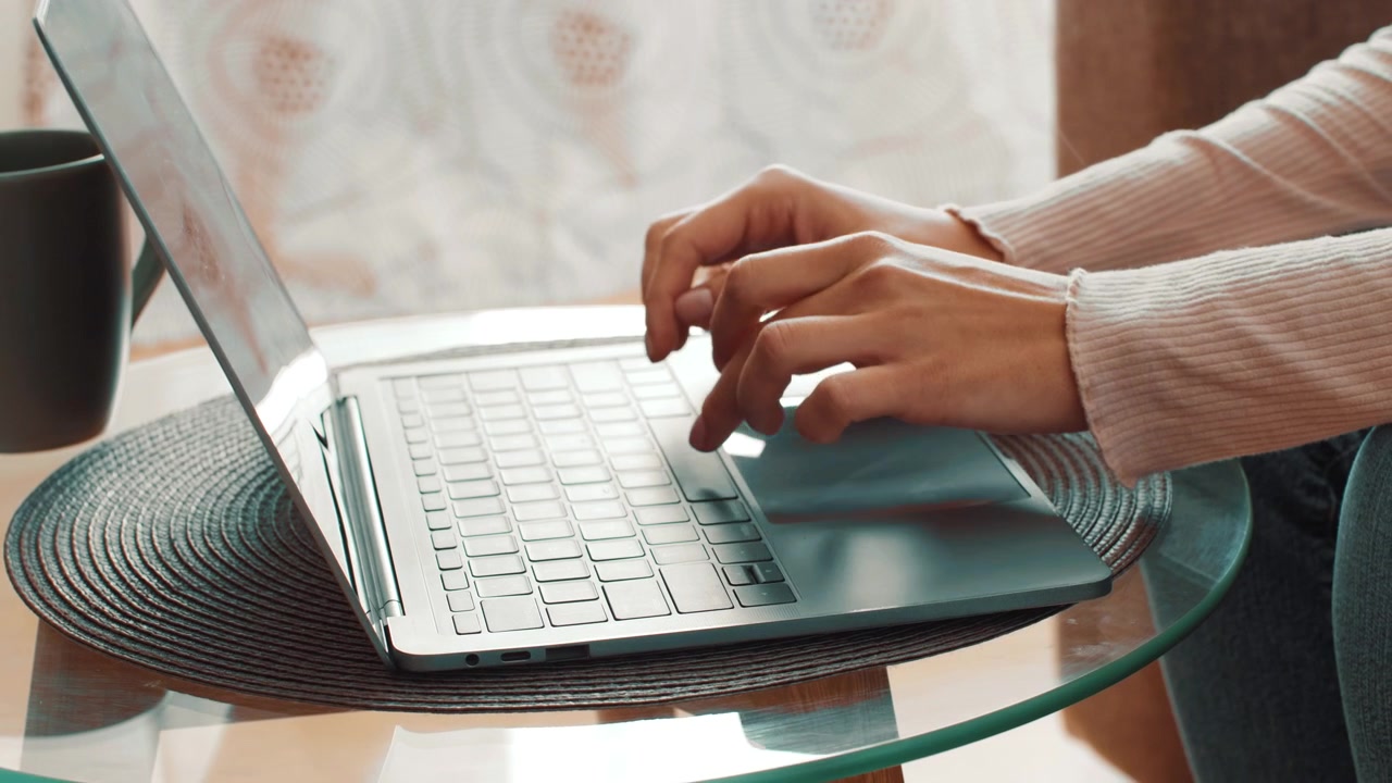 Persona che digita su un laptop a un tavolo di vetro