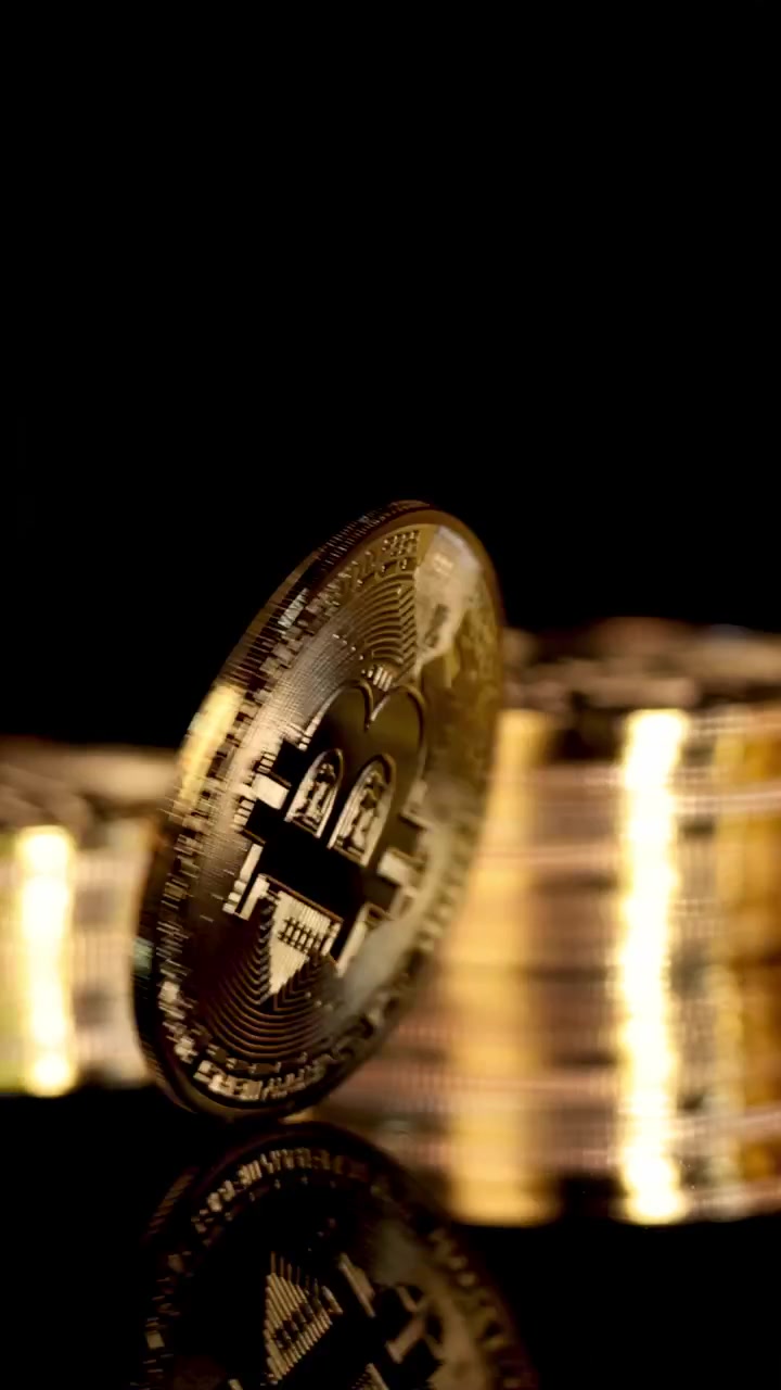 Moeda de Bitcoin Dourada Gira e Pousa em Superfície Reflexiva, Iluminação Dramática, Close-up, Fundo Preto