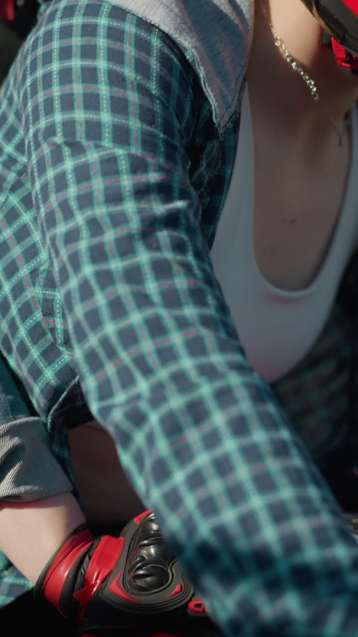 dos damas viajan por una carretera urbana en una bicicleta eléctrica, pasando por edificios y un coche estacionado, el collar del jinete se mueve con el movimiento de la bicicleta, el fondo está ligeramente borroso