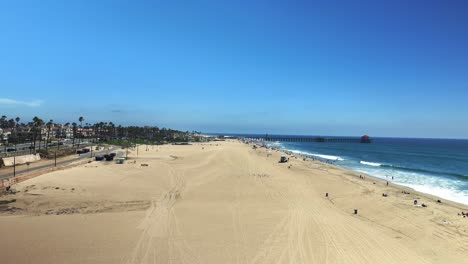 aerial view flying down the beach and towards the pier in huntington beach california