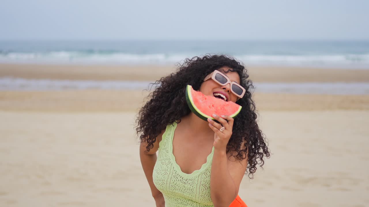 Mulher saboreando melancia na praia
