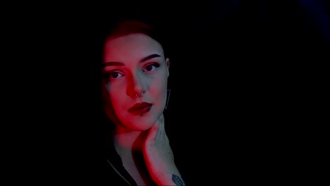 young attractive female model posing in front of a black background with red lighting