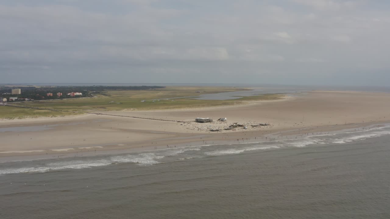 Drone - Aerial top shot of a restaurant, building with the sandy beach with tourists and people in St. Peter Ording at the north sea, schleswig holstein, germany, 30p