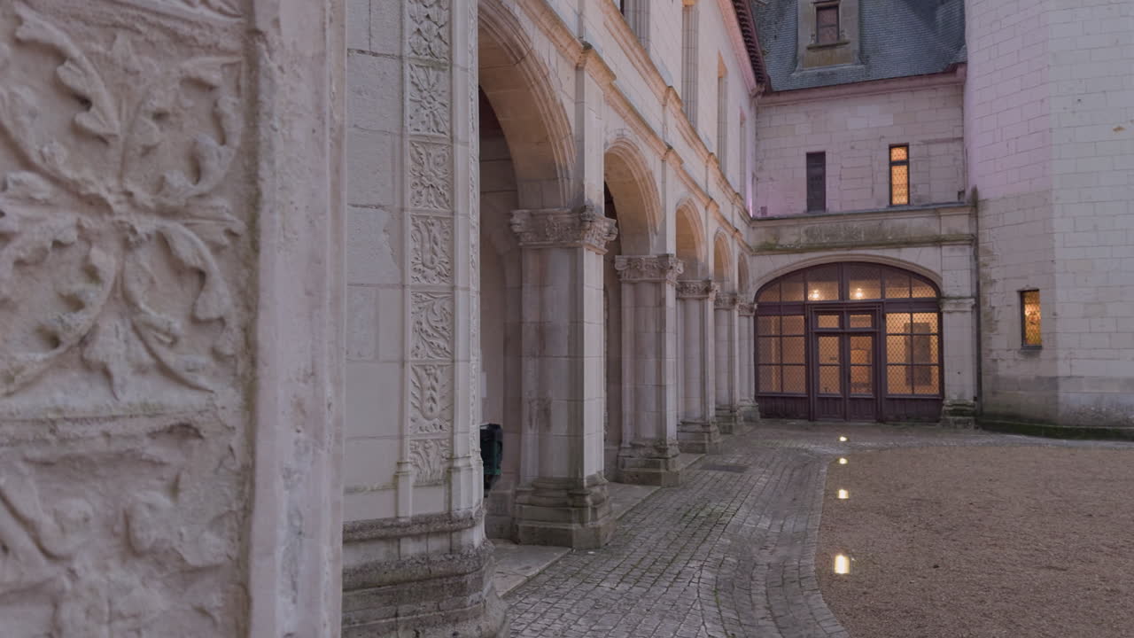 Ornate stone arches and illuminated walkway at Chaumont-sur-Loire at dusk create a historic ambiance