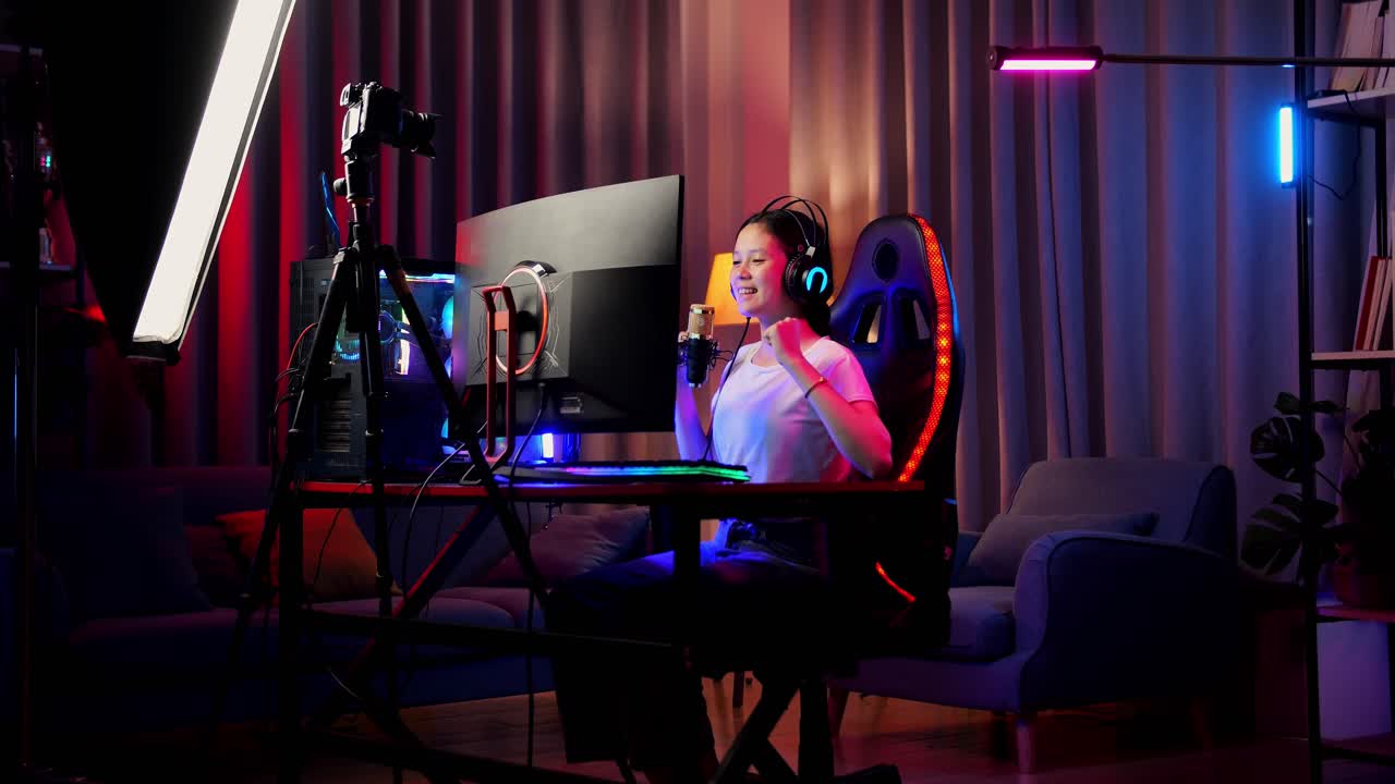 asian girl streamer gritando gol celebrando el juego ganador a través de la red en la computadora personal. videojuego de transmisión en vivo, escritorio iluminado por luz de tira de led rgb