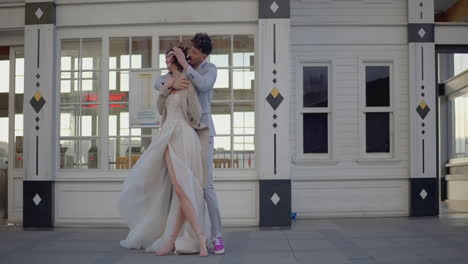 couple dancing in front of a white building