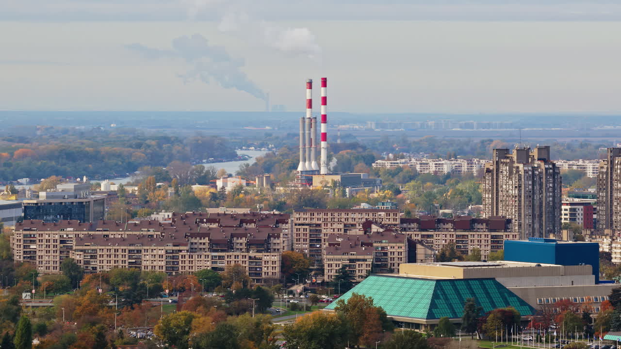 Aerial drone view of Novi Beograd, Serbia, highlighting large residential block buildings and the distinctive chimneys of the Novi Beograd heating plant in the distance