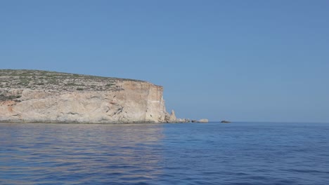 View-from-the-sea-waters-of-Malta's-other-main-islands,-known-as-Gozo,-showcasing-dramatic-cliffs-lining-the-Mediterranean-Sea