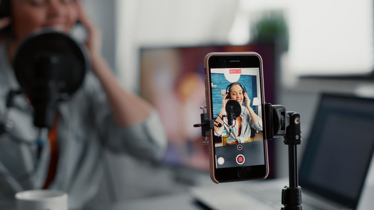 Social media content creator recording vlog with touchscreen phone while talking to audience