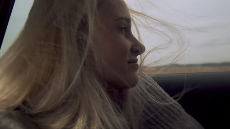 Beautiful-young-girl-relaxing-in-car-back-seat,-wind-in-hair,-slow-motion