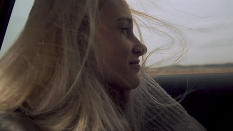 hermosa joven relajándose en el asiento trasero del auto, viento en el cabello, cámara lenta