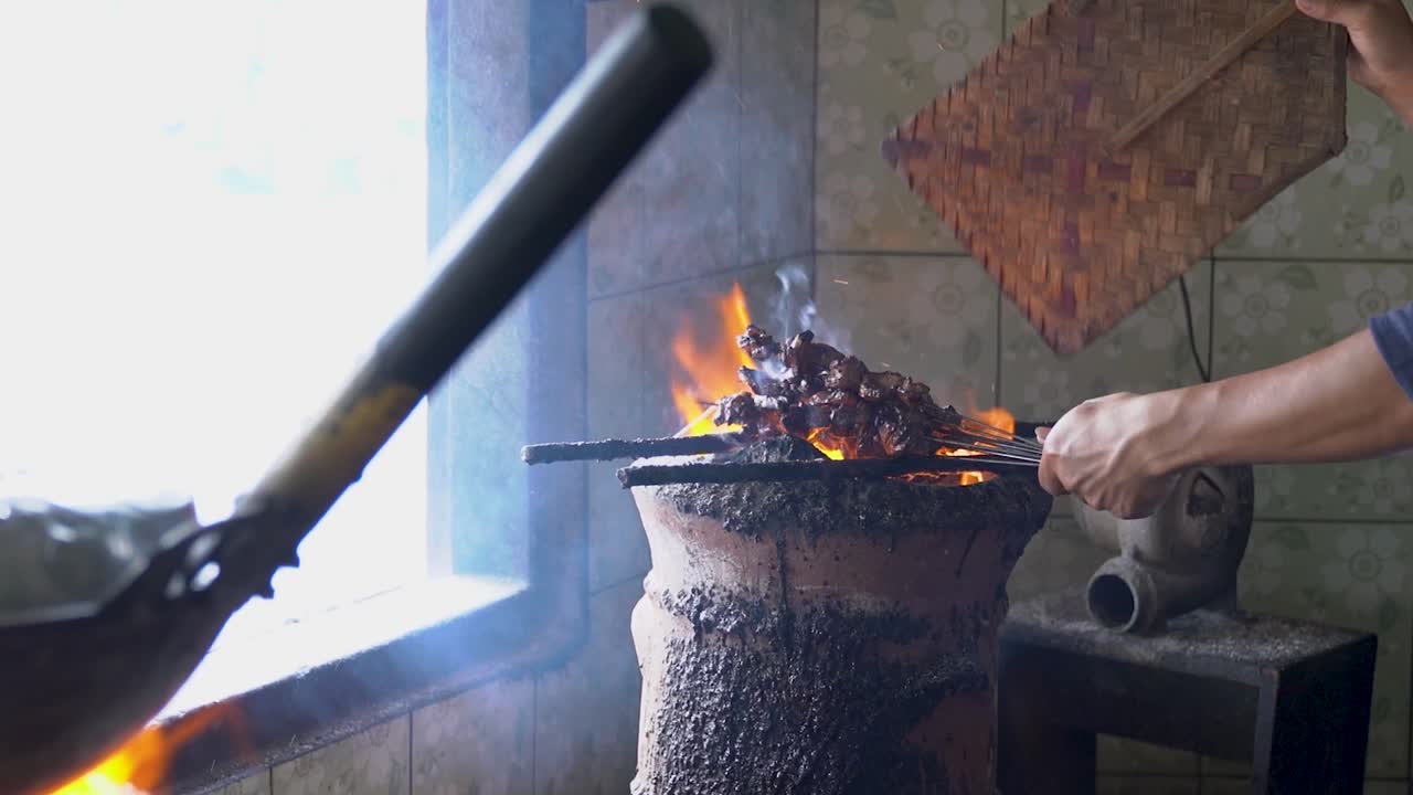 persona indonesia cocinando cordero fresco en barbacoa de llama abierta, vista de cerca
