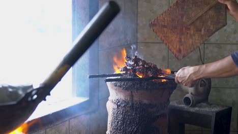 indonesian person cooking fresh mutton on open flame barbecue, close up view