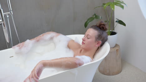 relaxing in bathtub with foam, young woman enjoying spa at home