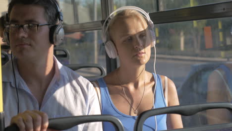 woman and man listening music in headset during bus trip