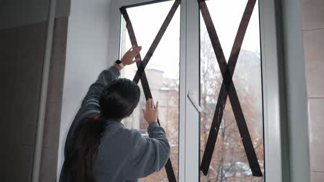 woman repairing a window with black tape