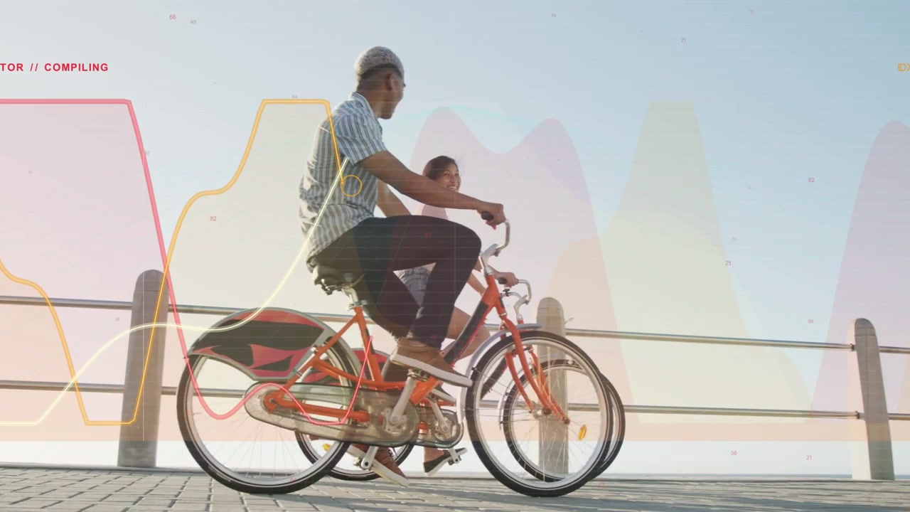 Ett par cyklar på orange cyklar längs strandpromenaden, rörelse skapar vågformer och etiketter för marknadsföring.
