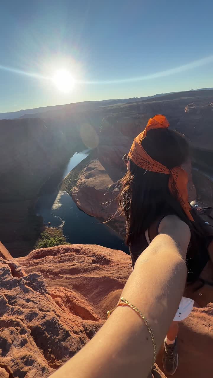 Mulher feliz fazendo trilha em um penhasco de rocha vermelha com vista para um cânion cênico