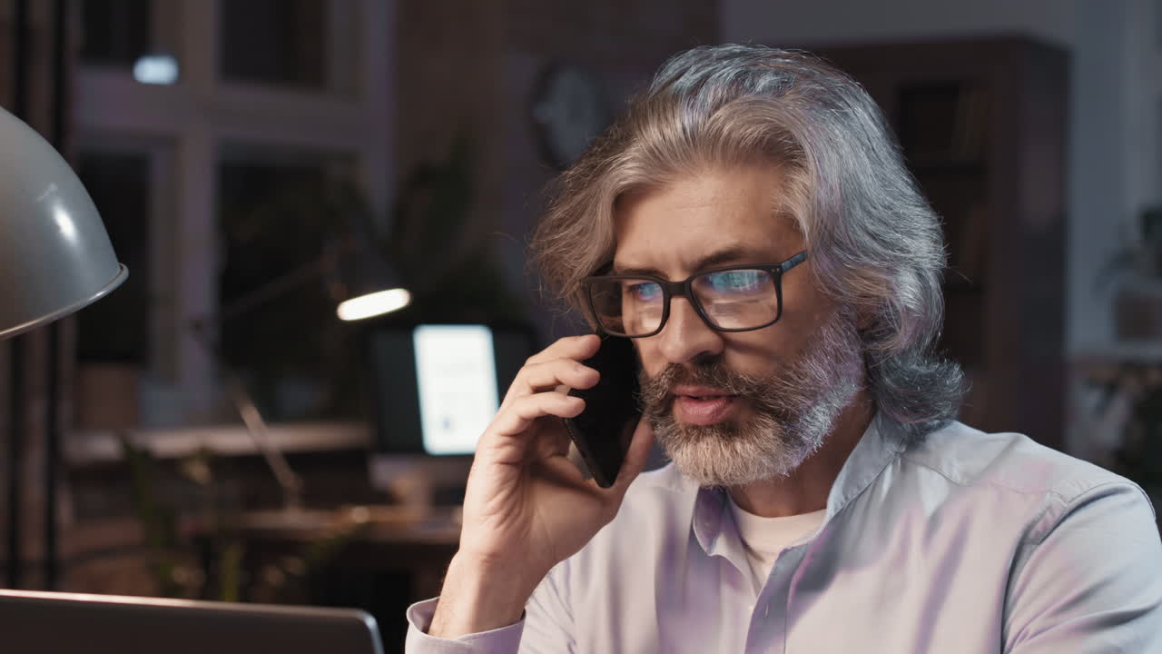 Mature man talking on a smartphone in an office setting
