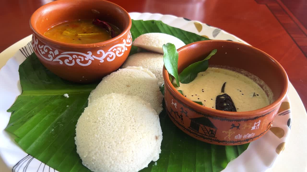 A Terracota cups with sambar and chutney includes idly on a banana leaf