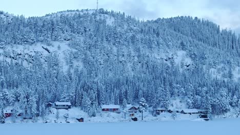 Snow-Covered-Cabin-And-Forest-During-Winter-In-Norway---Aerial-Shot