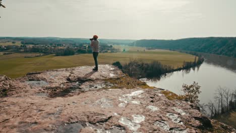 forward tracking shot of a photographer taking pictures at sunset on the edge of a cliff